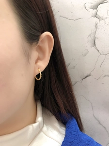Close-up of golden hoop earring with beaded texture worn on ear for fashion look
