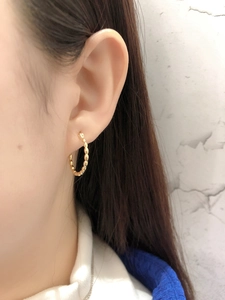 Detailed close-up of gold beaded hoop earring featuring a unique textured sphere design