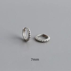 Detail of 7mm S925 sterling silver huggie earrings with a delicate beaded surface design