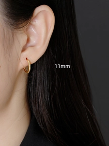 Detailed view of 11mm gold beaded hoop earrings worn on a model showcasing the textured finish