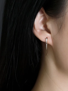 Vue macro d'une boucle d'oreille en argent avec zircon rectangulaire et pendentif conique