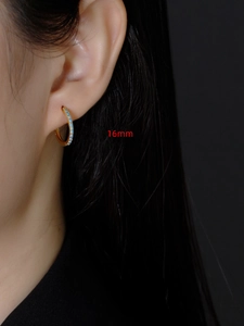 Detailopname van 16mm gouden oorringen met turquoise zirkoon gedragen door model