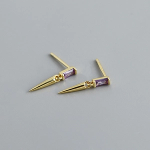 Détail de boucles d'oreilles dorées avec zircon violet et pendentif pic conique
