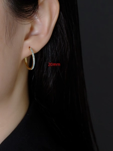 Close-up van 20mm gouden oorringen met turquoise steentjes gedragen door een model