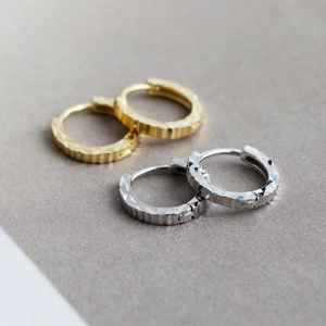Detalle de pendientes de aro de plata S925 en oro y plata con textura de corte de diamante