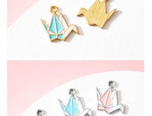 Détail de breloques en forme de grue en origami avec émail coloré et finition dorée