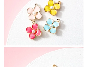 Detailed macro view of four colorful enamel flower charms with pearls in gold plating