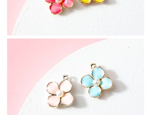 Macro detail of alloy flower charms with enamel petals, white pearl center and gold edging