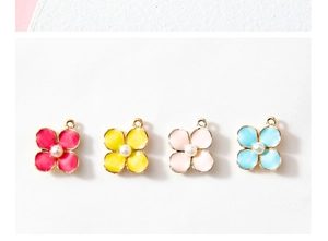 Close-up of four colorful floral alloy charms with faux pearl centers for DIY jewelry