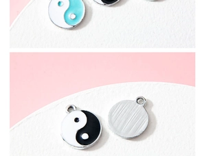 Detailed macro of Yin Yang enamel charms showing front drip oil and brushed metal back finish