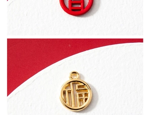 Macro detail of round hollow Fu character pendants in polished gold and red finish