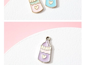 Macro shot of colorful enamel baby bottle charms with heart patterns for DIY jewelry