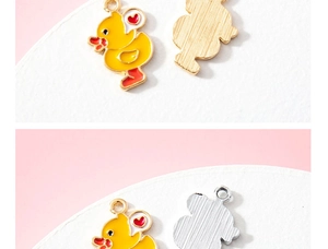 Vue détaillée des pendentifs canard en émail jaune avec accents de cœur rouge en or et argent