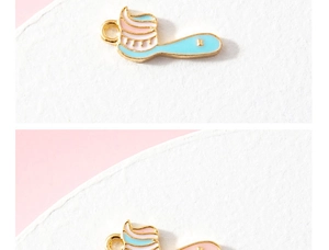 Macro detail of cute toothbrush and toothpaste enamel charms with gold metal edges