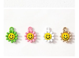 Dettaglio macro di ciondoli a girasole smaltati DIY in verde, rosa, bianco e finitura oro
