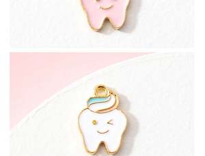 Close-up of cute pink and white enamel tooth charms for DIY jewelry making
