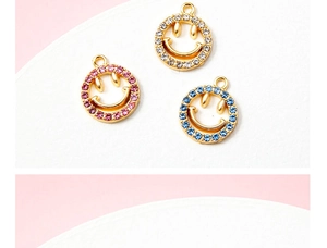 Detail van vergulde smiley-hangers met glanzende roze, blauwe en witte strass-steentjes