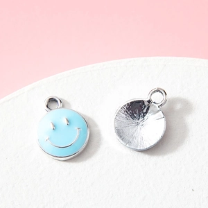 Light blue enamel smiley face charm with silver textured back on pink background