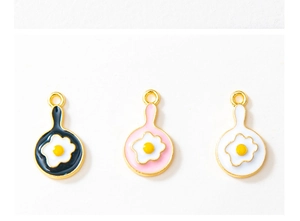 Close-up of fried egg frying pan alloy charms in black, pink, and white for DIY jewelry