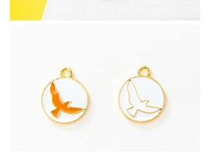 Detail of round golden eagle pendants with orange and white enamel for DIY jewelry