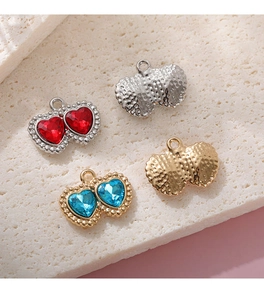 Dettaglio di ciondoli a doppio cuore in strass con bordi metallici in oro e argento