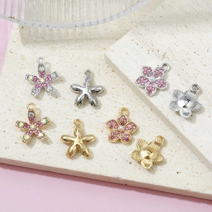 Pendenti a fiore fai-da-te con strass rosa e perle su superficie in pietra ruvida