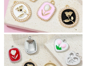 Macro detail of alloy floral heart charms with pearl borders and enamel flower patterns