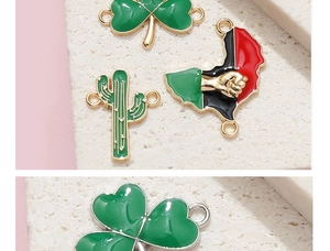 Makro-Detail von Emaille-Blattanhängern und einem Faust-Karten-Charm für DIY-Schmuck