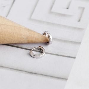 Detailopname van S925 sterling zilveren oorringen met een gefacetteerde diamantgeslepen textuur