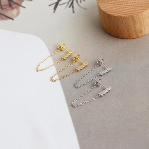 Detail of silver and gold tassel chain stud earrings with paved sparkling zircons