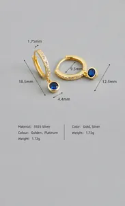 Détail macro des boucles d'oreilles en argent S925 avec gemme bleue et finition dorée