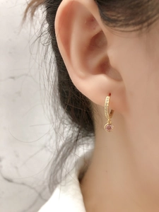 Gros plan de boucles d'oreilles créoles dorées avec pendentif gemme rose sur mannequin