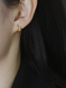 Gros plan de créoles en argent sterling S925 doré avec motif de cœur portées à l'oreille