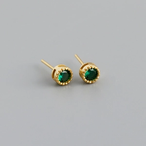Détail macro d'une boucle d'oreille en argent S925 avec zircon vert et finition dorée