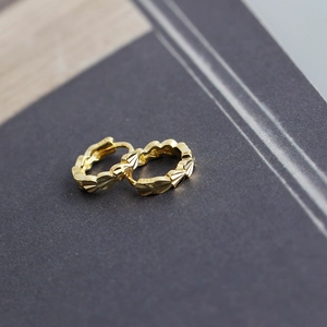 Macro shot of S925 sterling silver stamp on golden textured heart hoop earrings