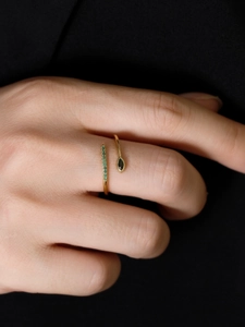 Detailed view of an adjustable gold ring featuring green pave crystals and a marquise stone