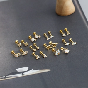 Dettaglio macro di borchie labret in argento 925 opale con motivi di serpente e fiori su grigio