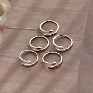 Detail view of five S-shaped silver rings set with multicolored zircons on wood