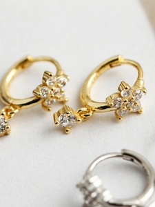 Détail macro de boucles d'oreilles fleur de prunier avec zircons scintillants en or