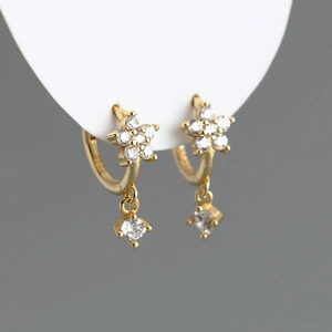 Vue macro de boucles d'oreilles fleur dorées avec pendentifs étoile et cristal brillant