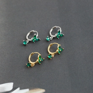 Macro detail of S925 butterfly earrings with green zircon stones in gold and silver