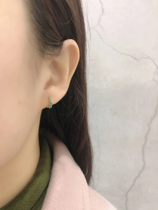 Gros plan de boucles d'oreilles créoles dorées avec perles turquoise sur un mannequin