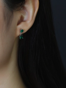 Close-up of S925 silver stud earrings with drop-shaped green zircon on a model