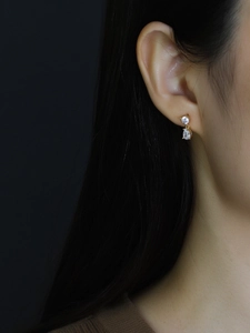 Close-up of model wearing gold drop earrings with pear-shaped cubic zirconia crystals