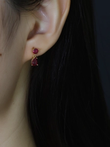 Close-up of red teardrop zircon earrings in gold-plated silver worn on ear