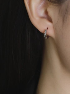 Close-up of a multifaceted s925 silver hoop earring worn on a model's earlobe