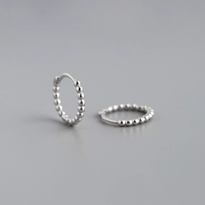 Detailed close-up of 925 sterling silver hoop earrings with a beaded textured design