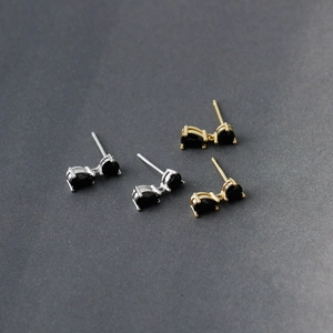 Macro view of gold and silver teardrop earrings featuring black cubic zirconia stones