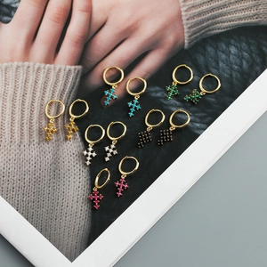 Détail de boucles d'oreilles créoles dorées avec pendentifs croix en zircons colorés
