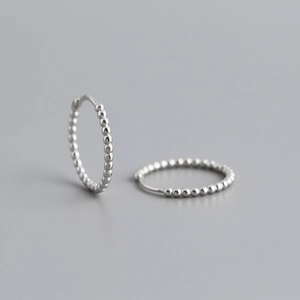 Macro shot of S925 sterling silver beaded hoop earrings with a modern textured surface